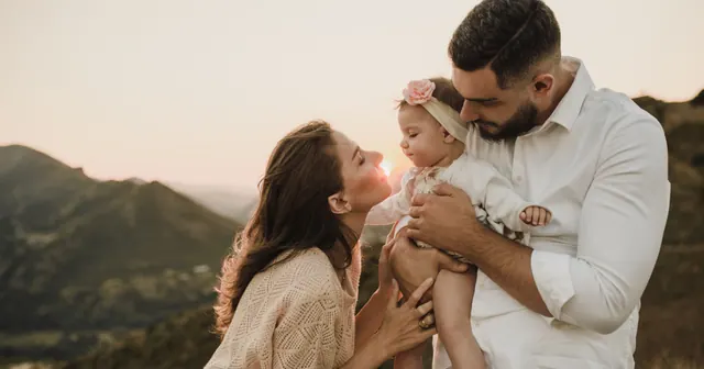 A family standing together on a hillside at sunset