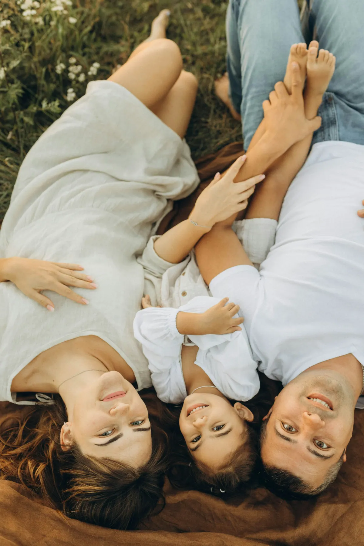 Three members of a family lying on a blanket with their heads together, seen from above