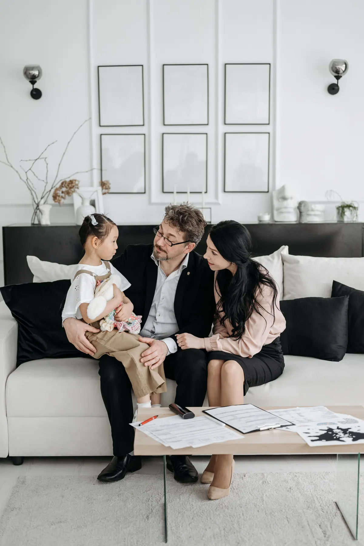A family seated on a living room sofa with printed pages spread on the table in front of them