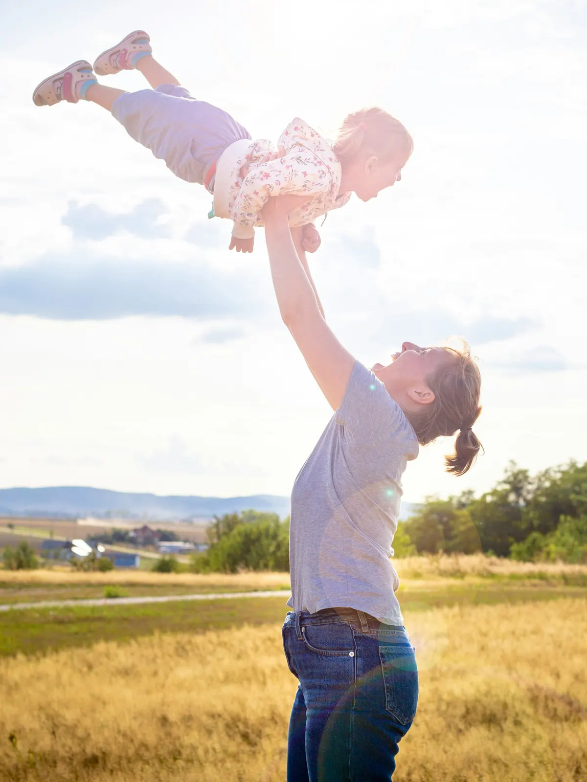 A father throwing a laughing baby into the air in an open field