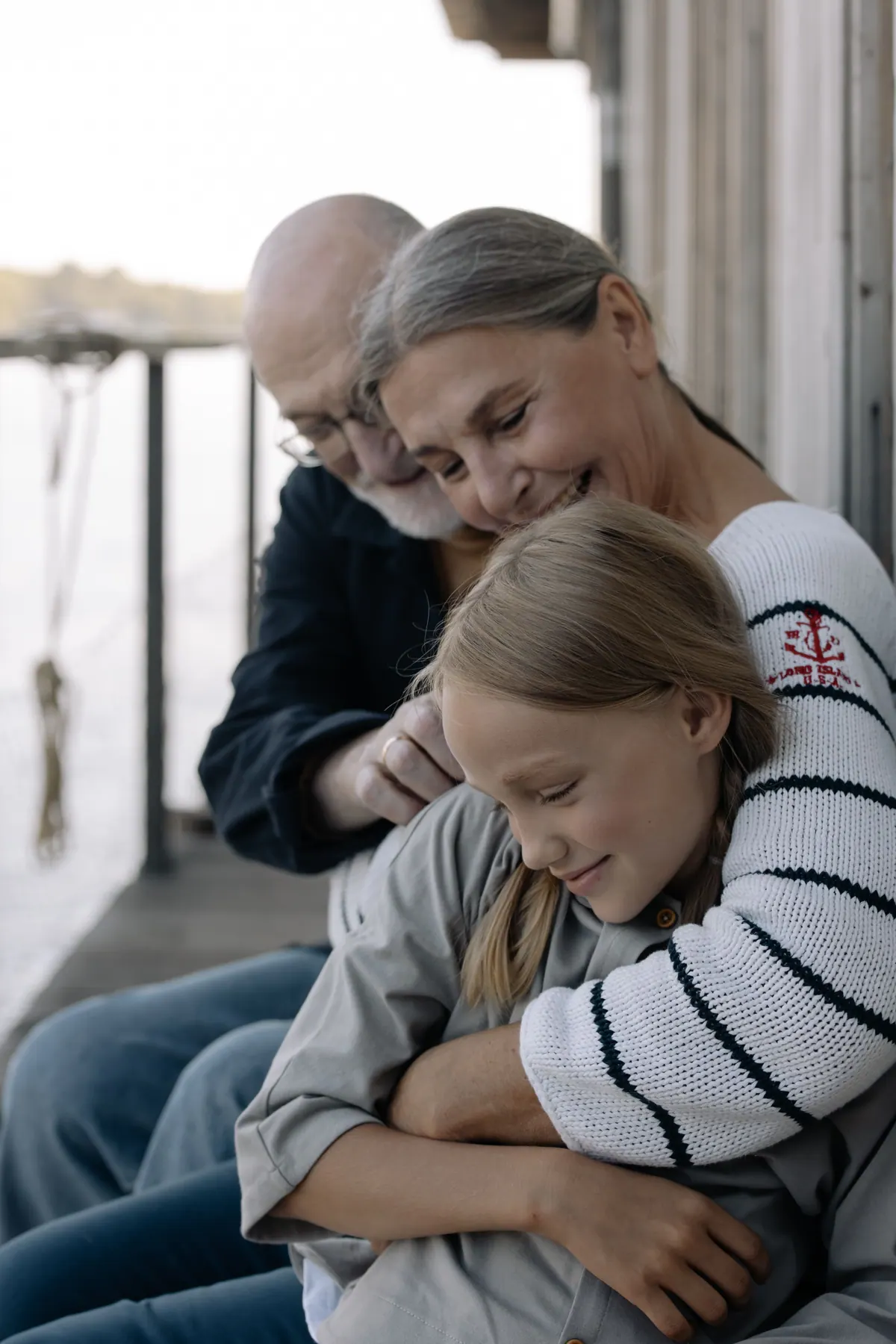 An older couple holding their granddaughter close while sitting outside