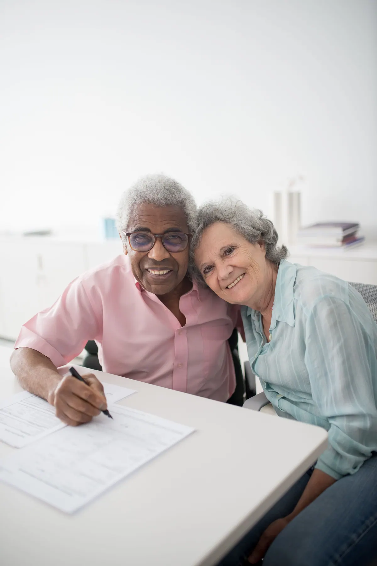 An older couple sitting at a desk completing a printed form together