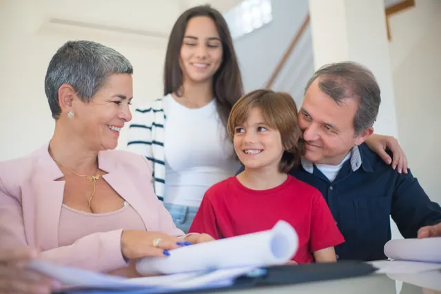 Three generations of a family gathered around printed documents at home