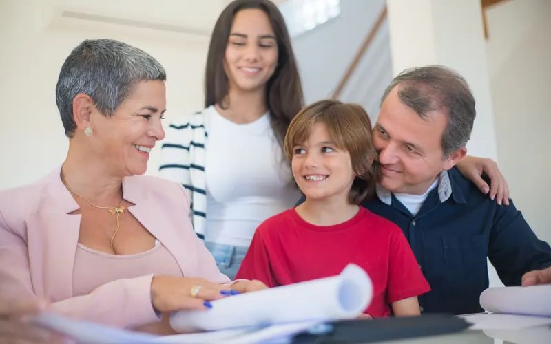 Three generations of a family gathered around printed documents at home