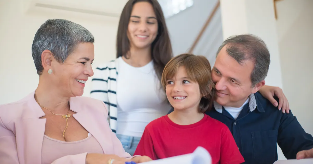 Three generations of a family gathered around printed documents at home